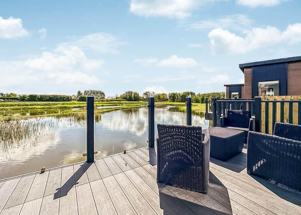 Private decking with rattan furniture and glass balustrade over the lake